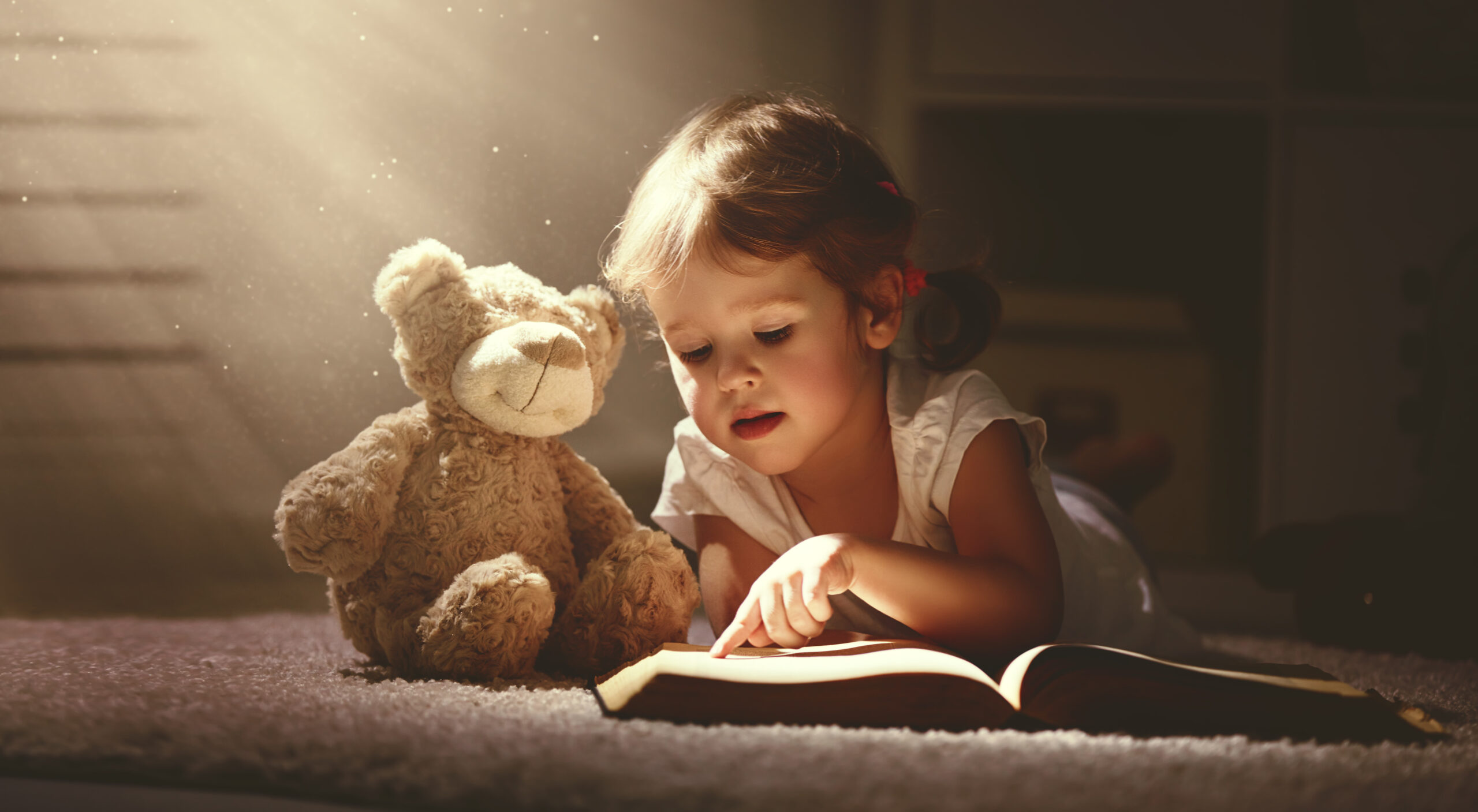 ילדה קטנה קוראת ספר על הרצפה בבית